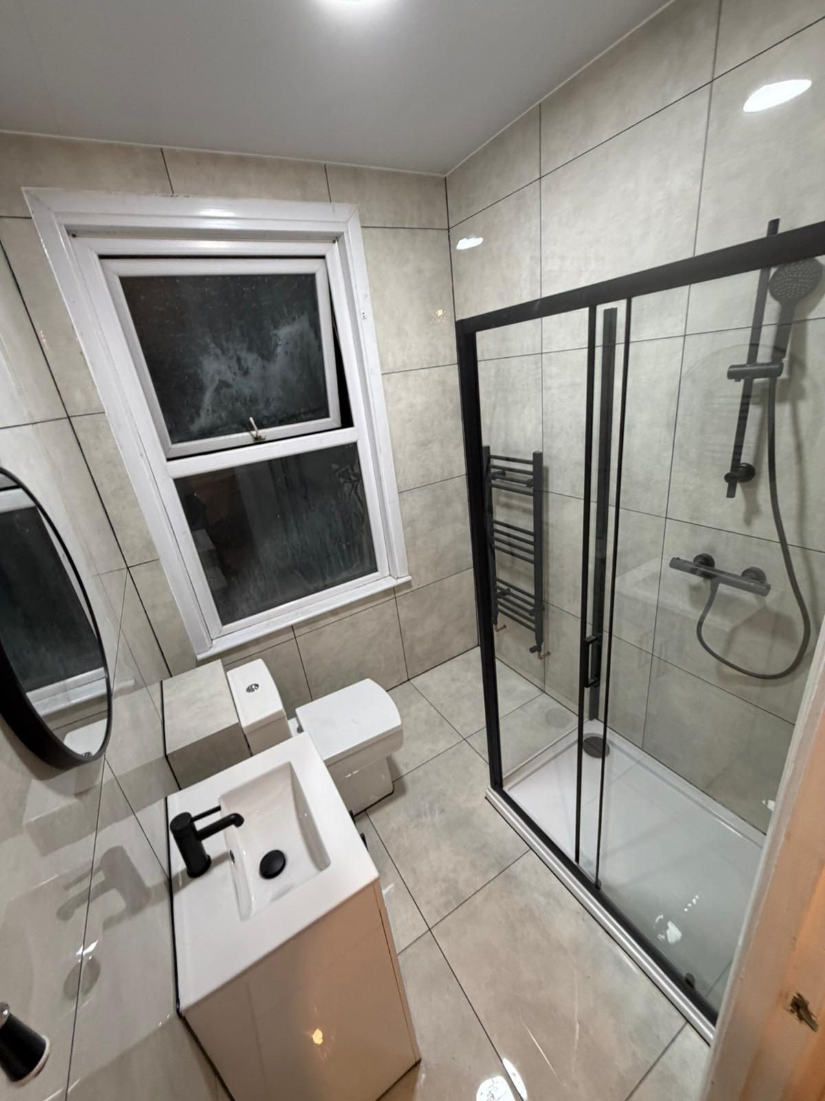 Modern bathroom with black-framed shower and heated towel rail