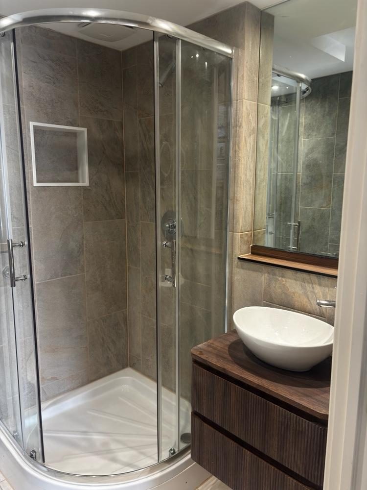 Stone shower enclosure with walnut vanity