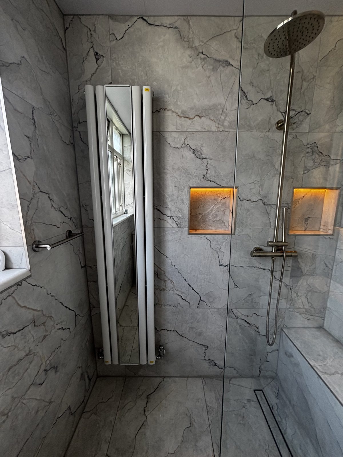 Marble-effect shower with rainfall head, linear drain and vertical radiator
