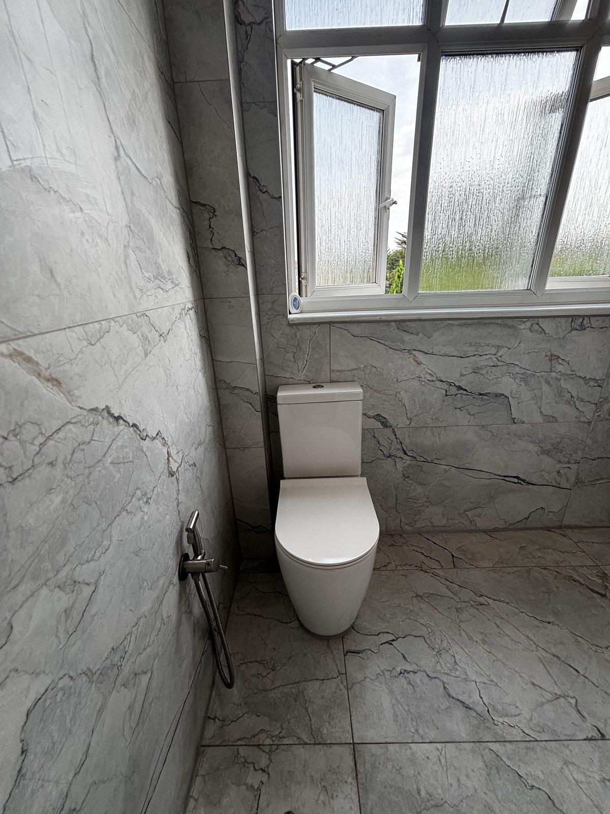 Marble-effect bathroom with close-coupled WC and douche spray